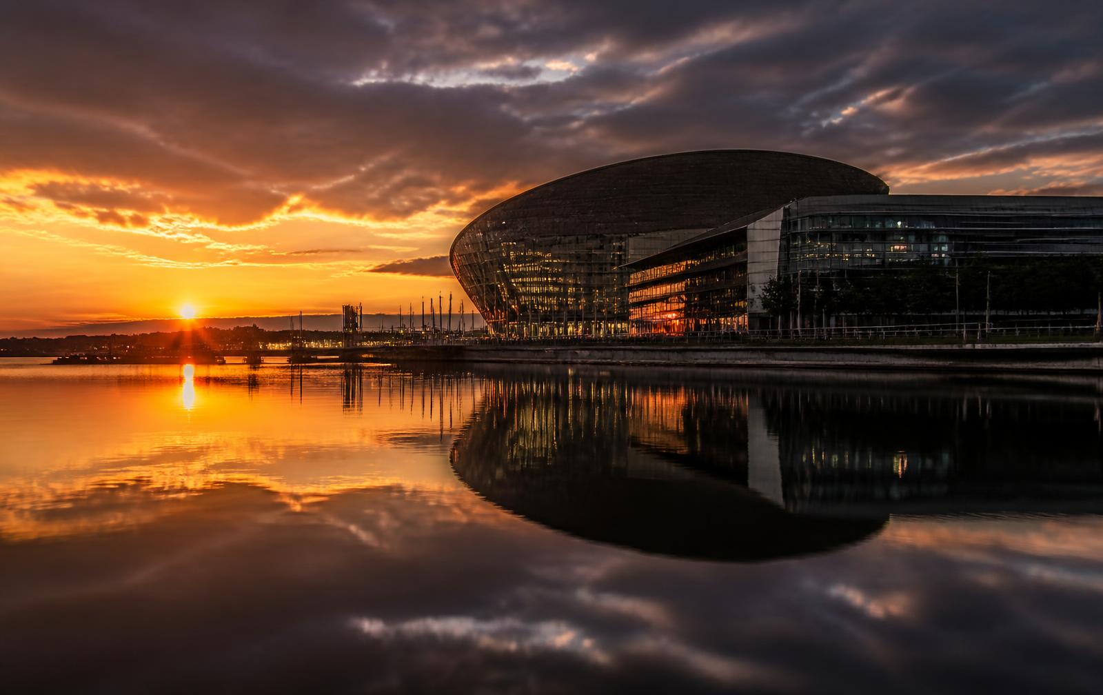 Cardiff Bay at sunset with the waterfront reflected in still water